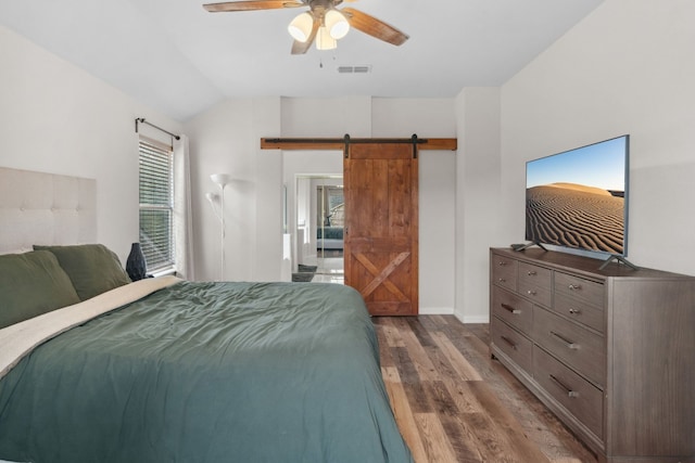 bedroom with lofted ceiling, a barn door, ceiling fan, and dark hardwood / wood-style floors