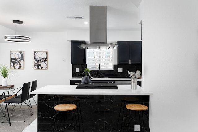 kitchen featuring sink, a breakfast bar area, decorative backsplash, island exhaust hood, and kitchen peninsula