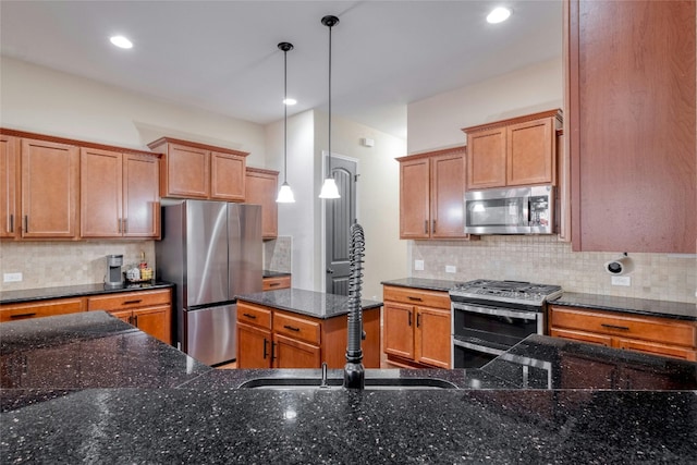 kitchen with pendant lighting, dark stone counters, sink, decorative backsplash, and appliances with stainless steel finishes