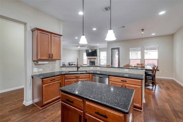 kitchen with dark hardwood / wood-style floors, sink, a fireplace, a kitchen island, and stainless steel dishwasher