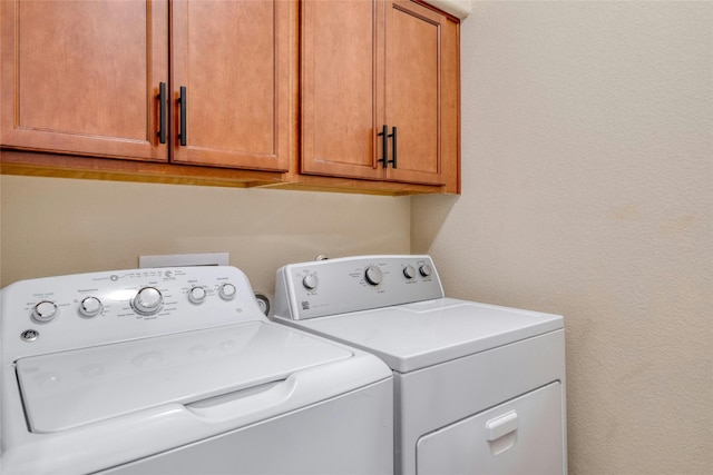 laundry area featuring washer and clothes dryer and cabinets