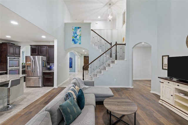 living room featuring hardwood / wood-style flooring, a towering ceiling, and a chandelier