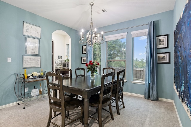 carpeted dining room with an inviting chandelier