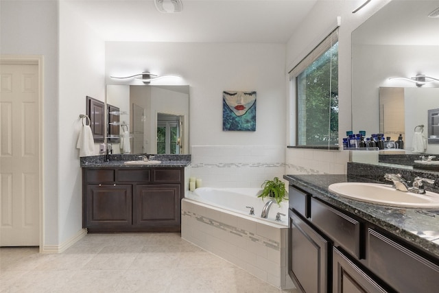 bathroom with tile patterned floors, tiled tub, and vanity