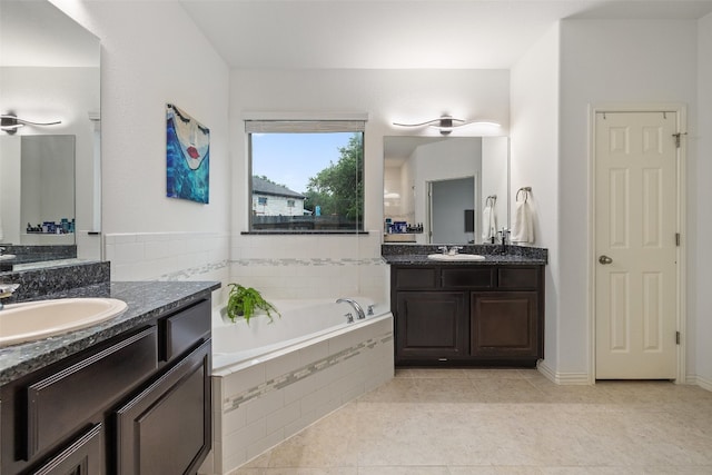 bathroom with tile patterned flooring, tiled bath, and vanity