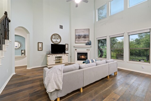 living room featuring a high ceiling, dark hardwood / wood-style flooring, and ceiling fan