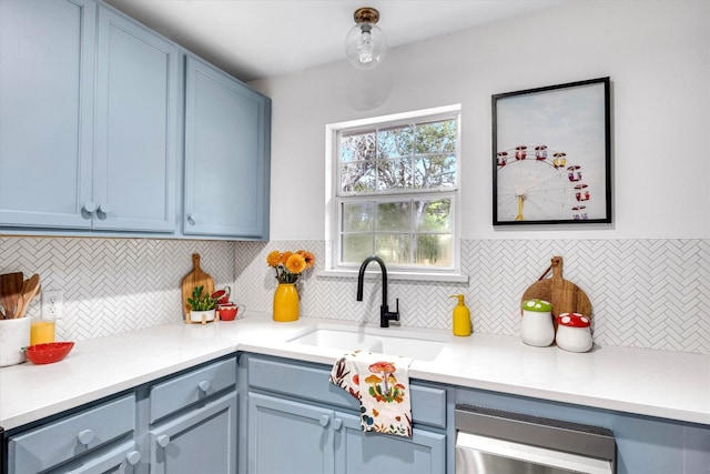 kitchen with backsplash, blue cabinetry, dishwasher, and sink