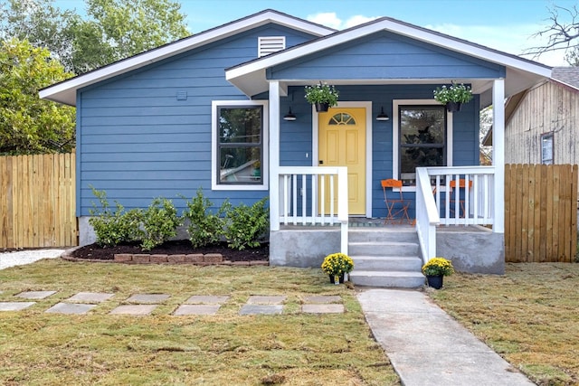 bungalow-style home featuring covered porch and a front yard