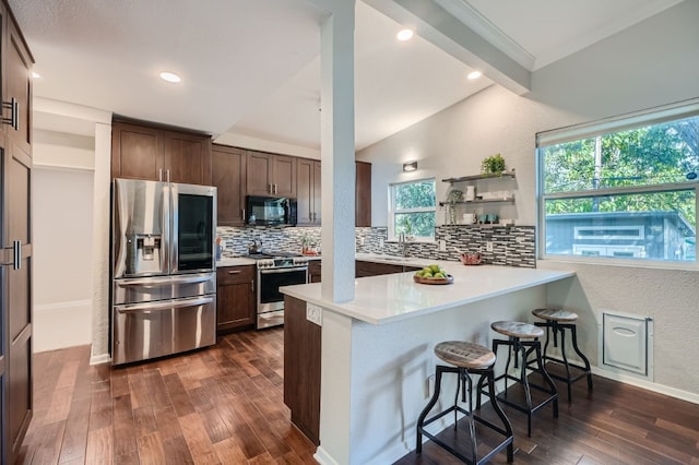 kitchen featuring lofted ceiling with beams, kitchen peninsula, a kitchen bar, stainless steel appliances, and dark hardwood / wood-style flooring