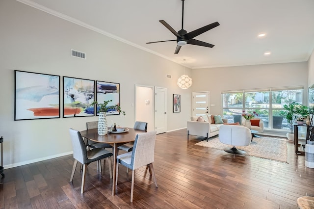 dining room featuring crown molding, a towering ceiling, dark hardwood / wood-style flooring, and ceiling fan