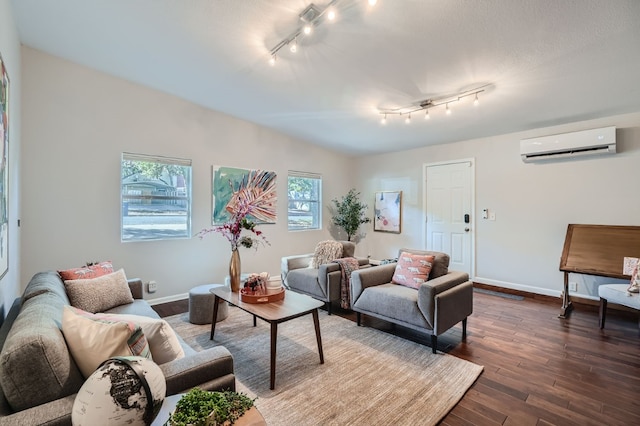 living room featuring rail lighting, dark hardwood / wood-style floors, and a wall mounted air conditioner