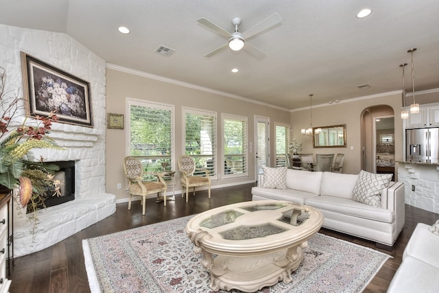 living room with a stone fireplace, ceiling fan with notable chandelier, dark hardwood / wood-style floors, and a healthy amount of sunlight