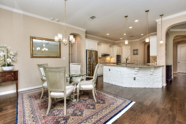 dining area with ornamental molding, sink, a chandelier, and dark hardwood / wood-style flooring