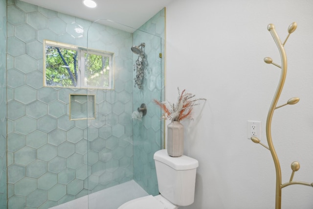 bathroom with a tile shower and toilet