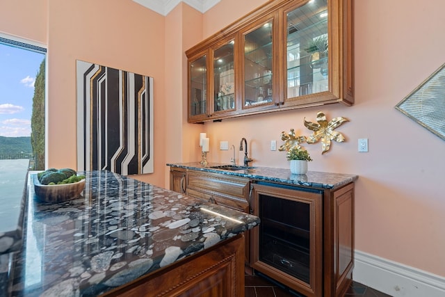 bar featuring ornamental molding, sink, and dark stone counters