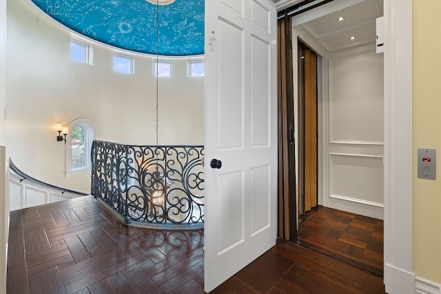 hallway featuring parquet flooring, ornamental molding, and elevator