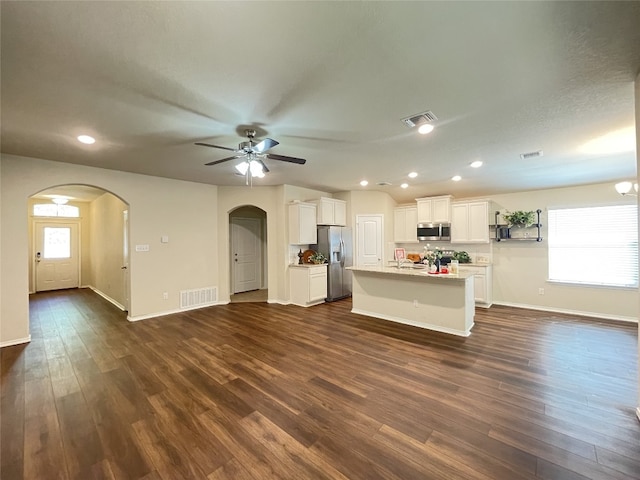 kitchen featuring white cabinetry, ceiling fan, dark wood-type flooring, stainless steel appliances, and an island with sink