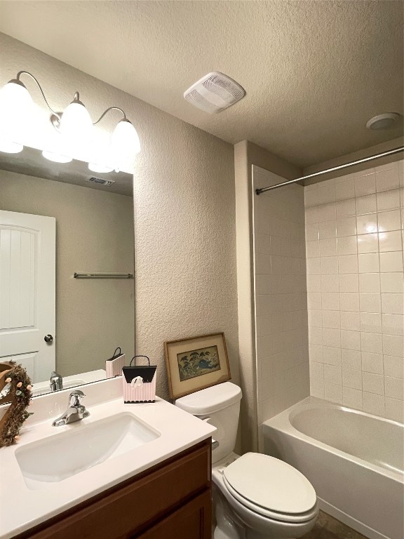 full bathroom with vanity, toilet, a textured ceiling, and tiled shower / bath