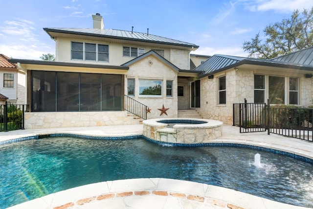 view of pool featuring a sunroom, pool water feature, and an in ground hot tub