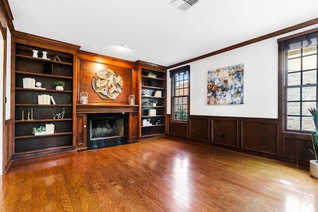 3605 Douglas Dr, Horseshoe Bay, TX 78657 - unfurnished living room featuring a fireplace with flush hearth, ornamental molding, wood finished floors, wainscoting, and built in features