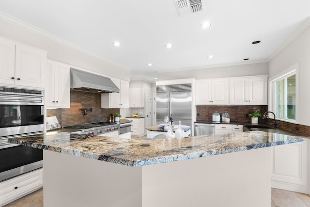 3605 Douglas Dr, Horseshoe Bay, TX 78657 - kitchen with wall chimney range hood, appliances with stainless steel finishes, decorative backsplash, dark stone countertops, and recessed lighting