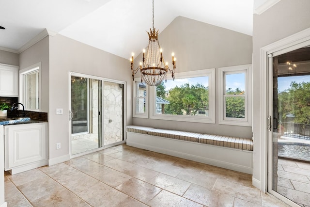 unfurnished dining area featuring a notable chandelier, sink, ornamental molding, and high vaulted ceiling