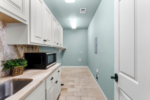 3605 Douglas Dr, Horseshoe Bay, TX 78657 - clothes washing area with baseboards, electric panel, and stone tile floors