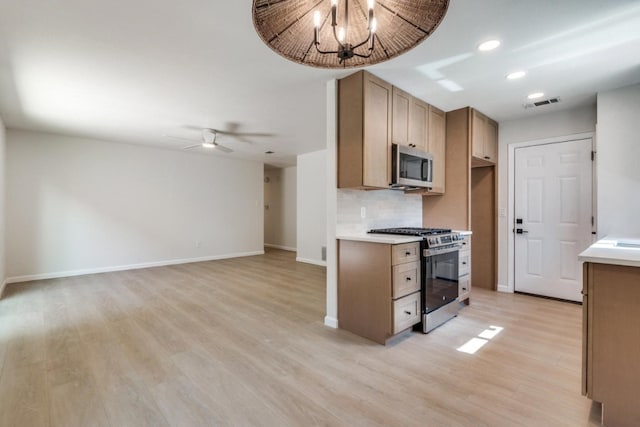 kitchen with backsplash, stainless steel appliances, light wood-type flooring, and ceiling fan with notable chandelier