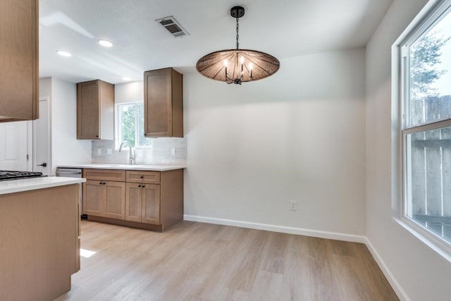 kitchen featuring tasteful backsplash, decorative light fixtures, sink, and light wood-type flooring