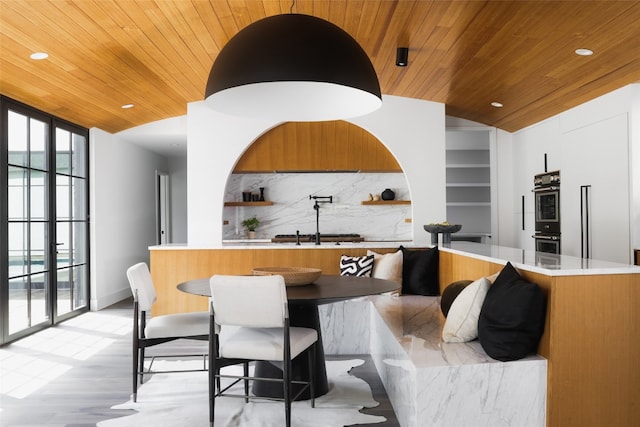 interior space featuring kitchen peninsula, light hardwood / wood-style flooring, backsplash, wooden ceiling, and vaulted ceiling