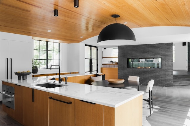 kitchen featuring wood ceiling, hardwood / wood-style flooring, sink, hanging light fixtures, and light stone countertops