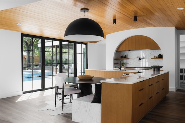 kitchen featuring decorative light fixtures, a center island, dark hardwood / wood-style flooring, and wooden ceiling