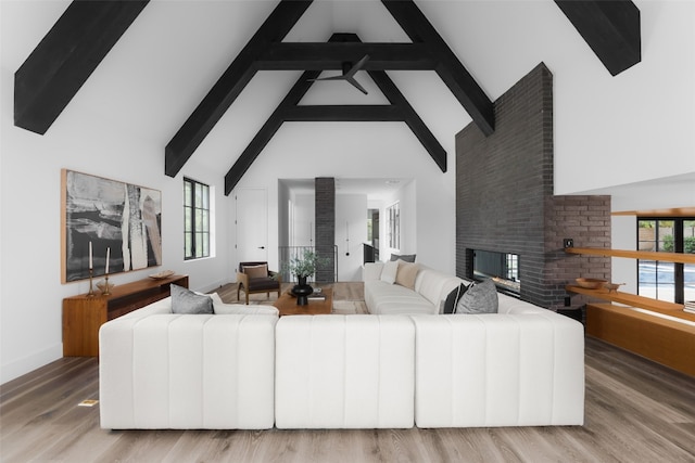 living room with a healthy amount of sunlight, a fireplace, hardwood / wood-style floors, and high vaulted ceiling