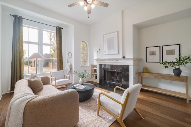 sitting room featuring a tile fireplace, ceiling fan, and dark wood-type flooring