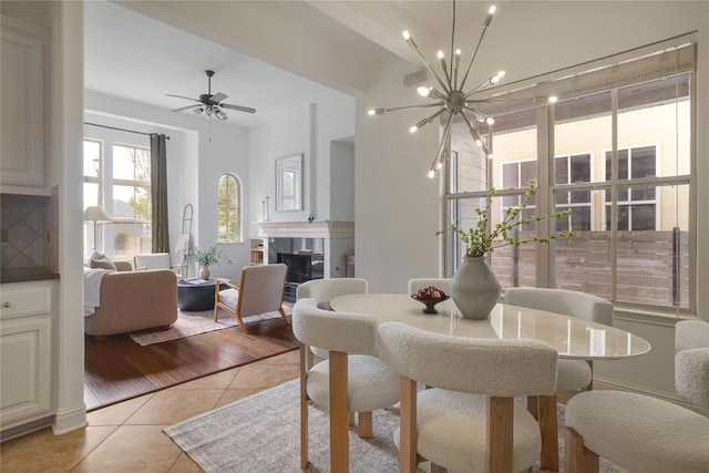 tiled dining room featuring ceiling fan with notable chandelier