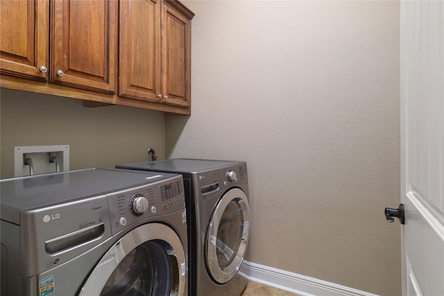 laundry room with tile patterned floors, washing machine and dryer, and cabinets