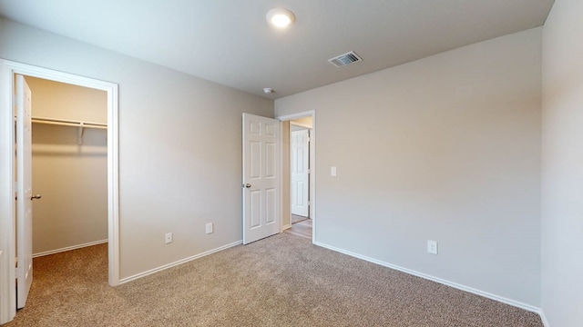 unfurnished bedroom featuring light carpet, a closet, and a walk in closet