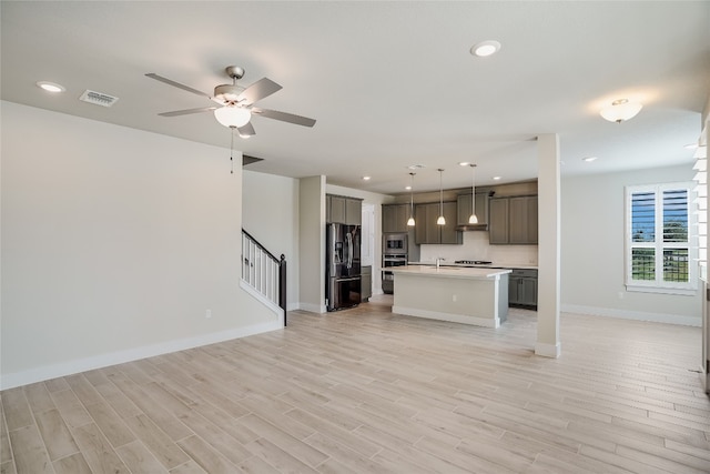 kitchen featuring hanging light fixtures, an island with sink, light hardwood / wood-style flooring, and stainless steel appliances