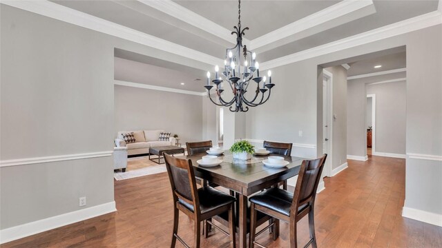 dining area with a chandelier, ornamental molding, and hardwood / wood-style flooring