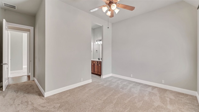 unfurnished bedroom with ceiling fan, light colored carpet, and ensuite bath