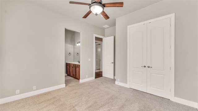 unfurnished bedroom featuring sink, ceiling fan, connected bathroom, light colored carpet, and a closet