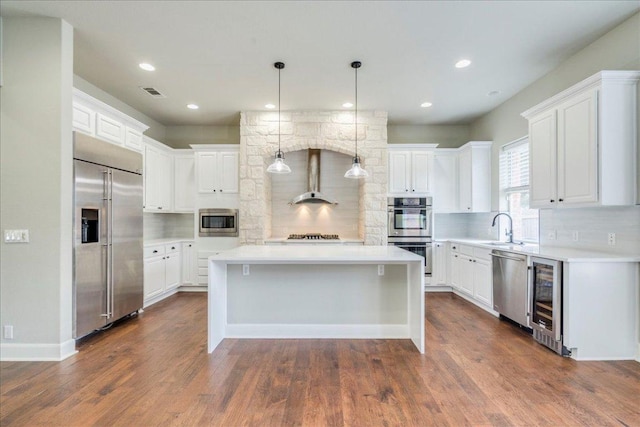 175 Blazing Star Dr, Austin, TX 78737 - kitchen with built in appliances, beverage cooler, wall chimney exhaust hood, a kitchen island, and decorative backsplash