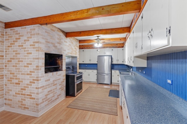 kitchen featuring white cabinets, beam ceiling, appliances with stainless steel finishes, ceiling fan, and brick wall