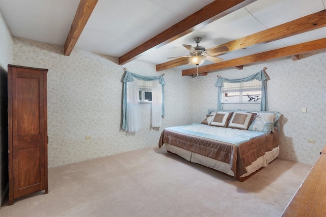 bedroom with ceiling fan, beamed ceiling, and light colored carpet