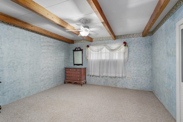 carpeted spare room featuring ceiling fan and beamed ceiling