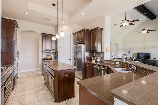 kitchen with ceiling fan, hanging light fixtures, sink, stainless steel appliances, and a center island