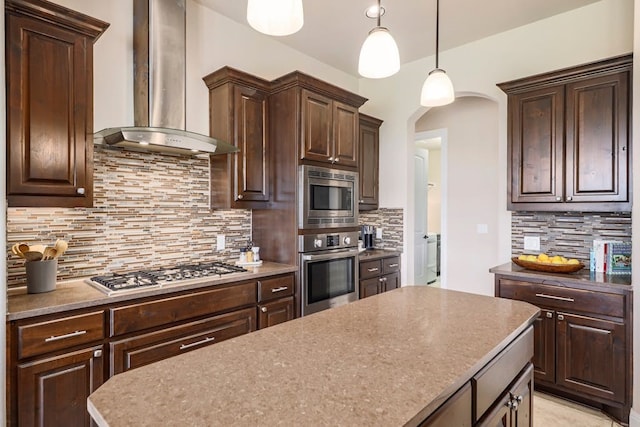 kitchen with backsplash, wall chimney exhaust hood, stainless steel appliances, and decorative light fixtures