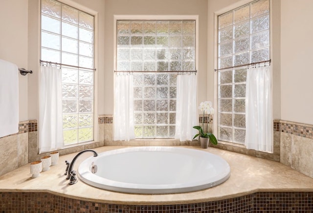 bathroom featuring tiled bath and a healthy amount of sunlight