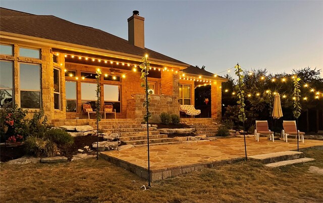 back house at dusk with a patio