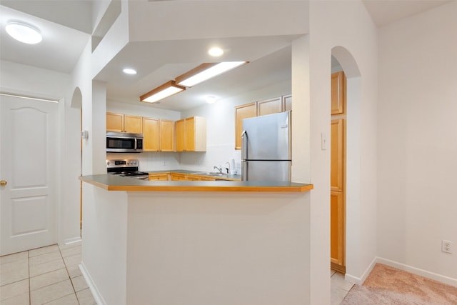 kitchen featuring kitchen peninsula, light brown cabinets, light tile patterned flooring, and appliances with stainless steel finishes